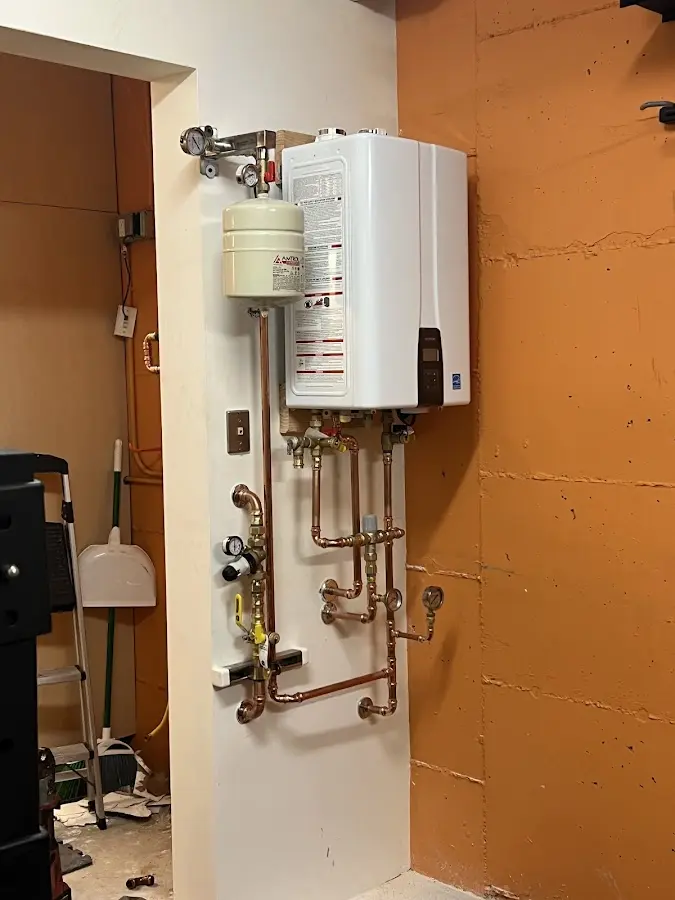 Plumbing technician inspecting water heater connections in North Hampton